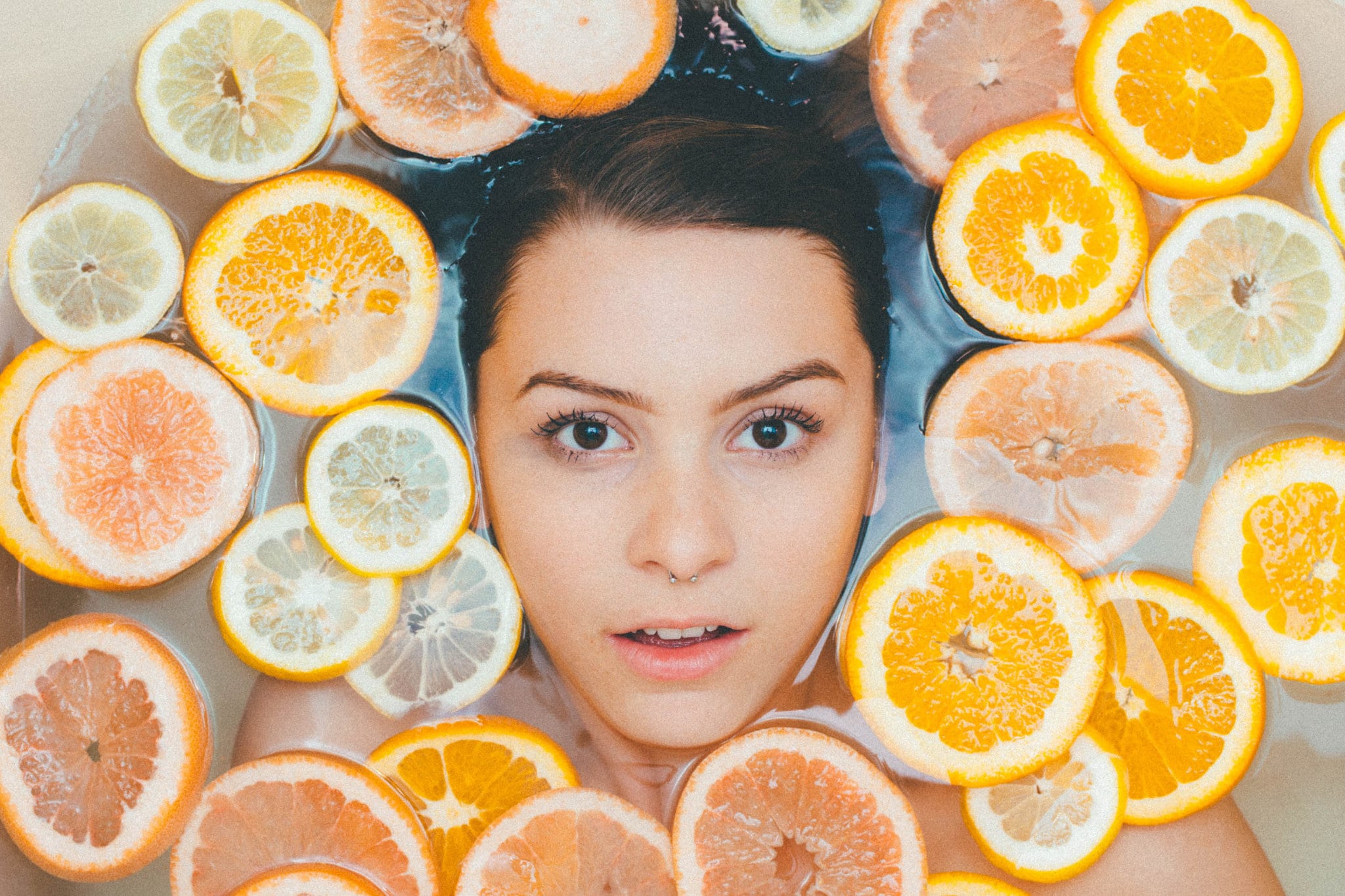 Vrouw in bad met stukjes citroen en sinaasappel
