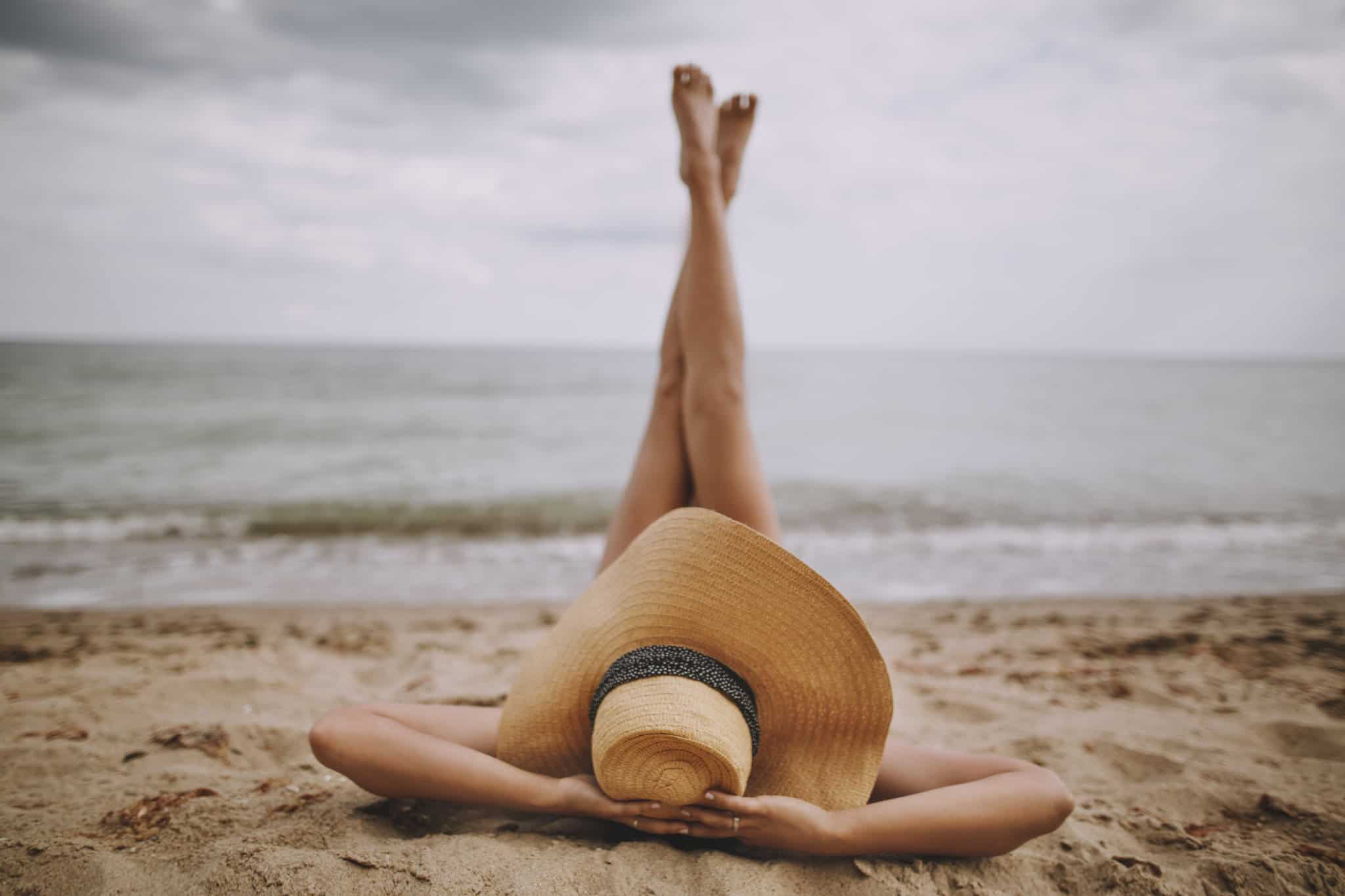 Vrouw op het strand met haar benen in de lucht