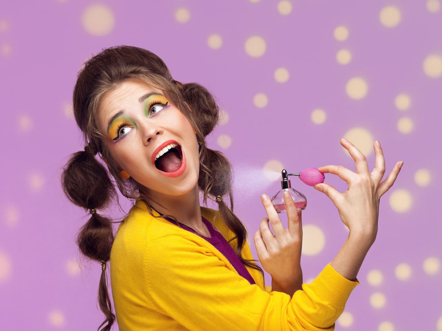 Young fancy woman applying perfume on dotted background