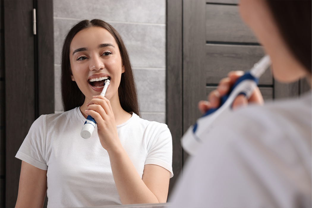 Vrouw poetst haar tanden met een elektrische tandenborstel