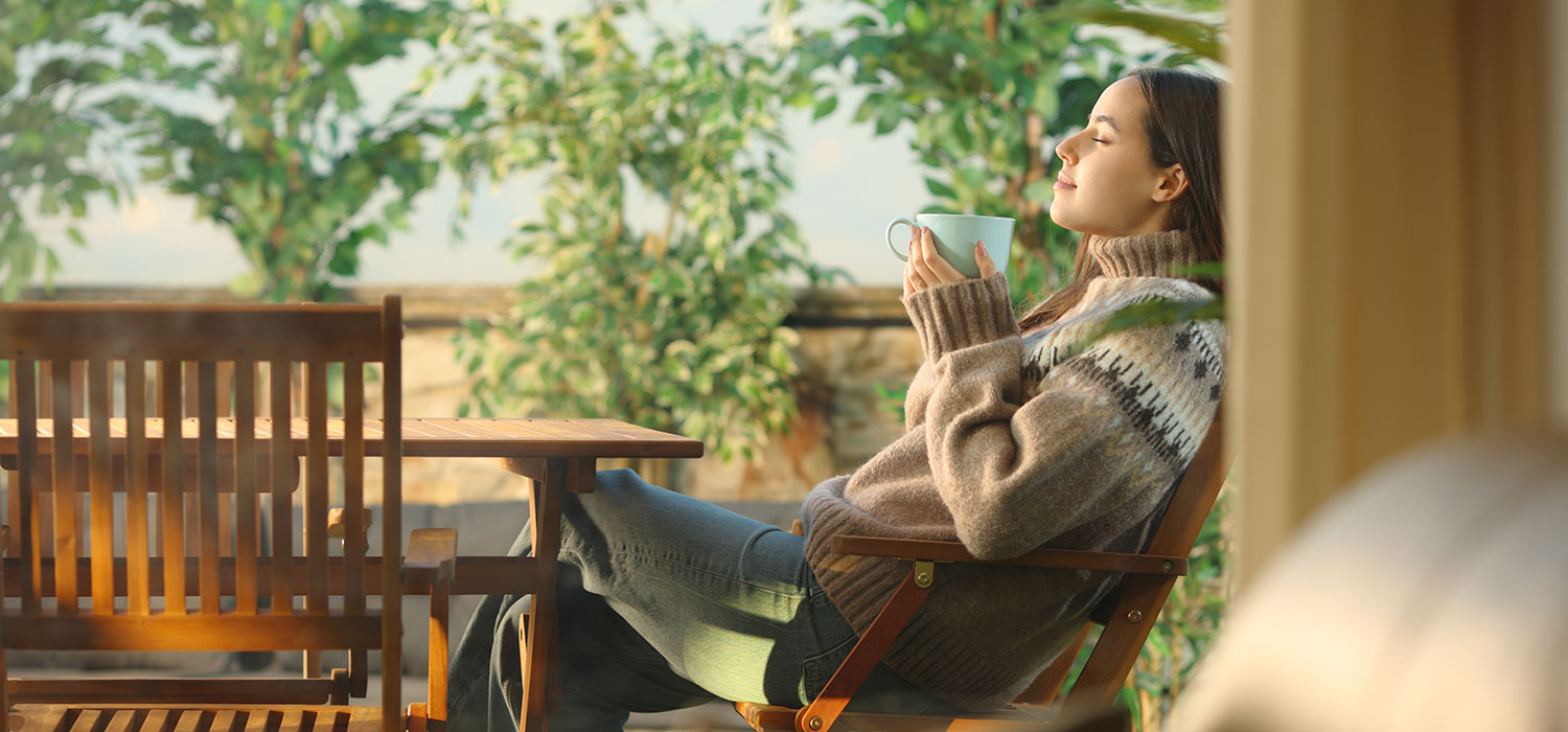 Vrouw drinkt koffie op het terras in de herfst 