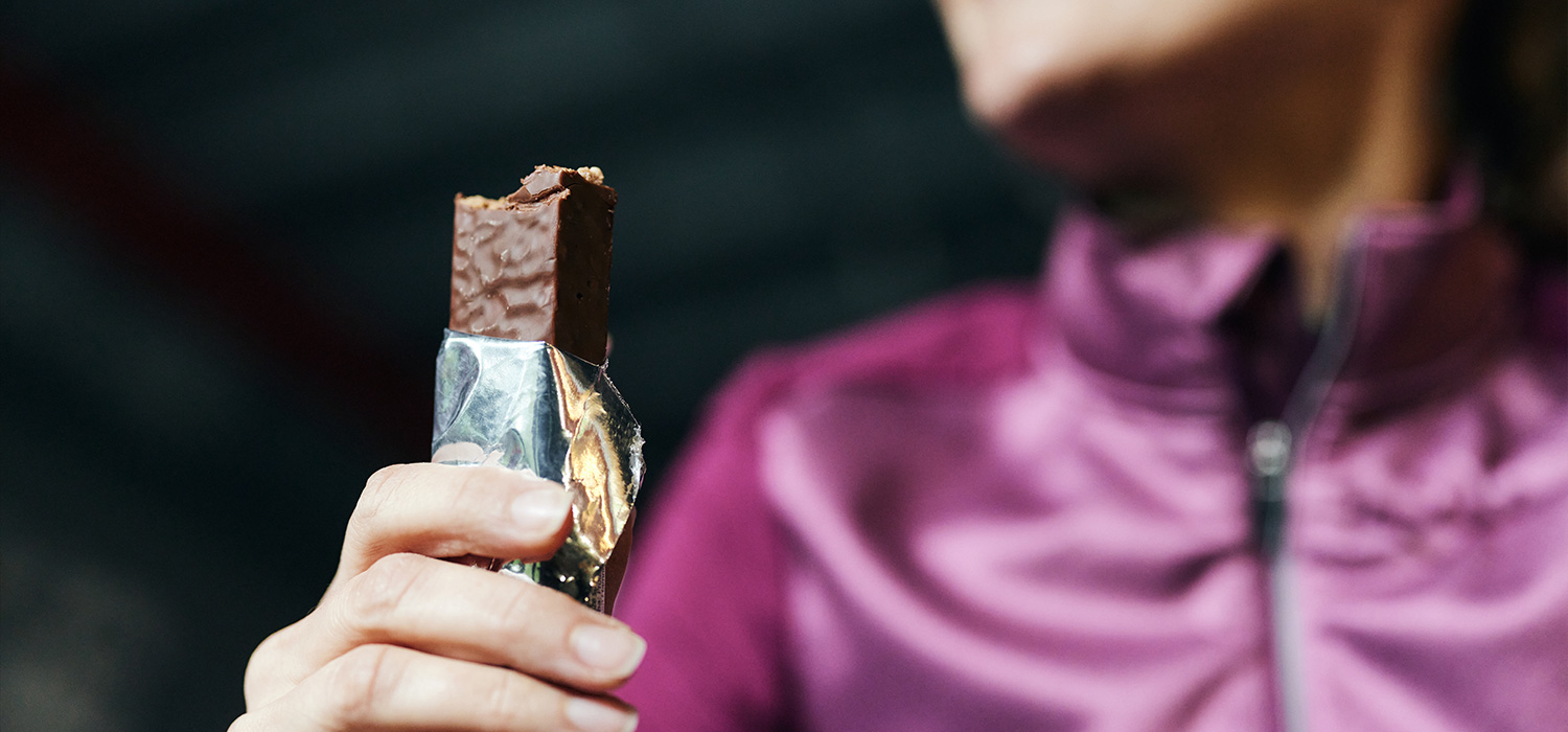 Vrouw eet een eiwitreep na het sporten